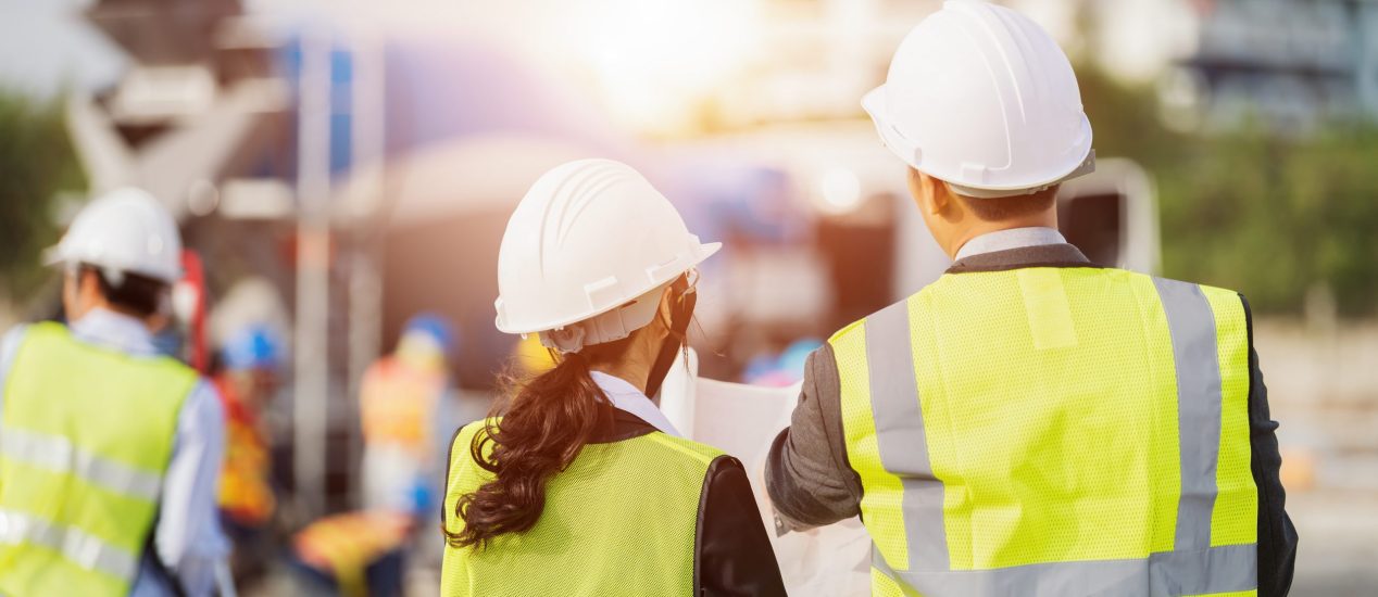 Businessman and businesswoman using see plan paper at construction site